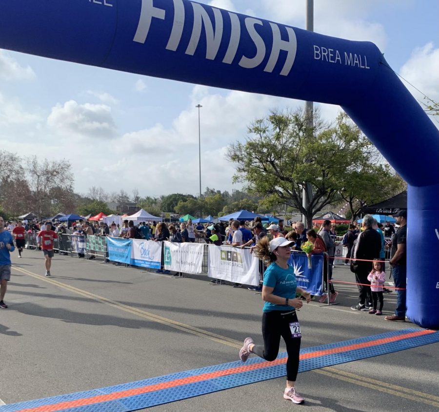 In last years Brea 8K race, Gloria Corona runs through the finish line of the 8K race course at the Brea Mall. This year, 8K runners will run their own course to accommodate COVID-19 restrictions.