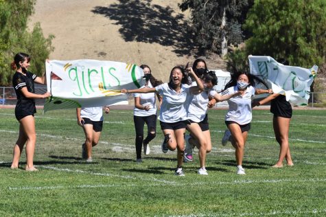 Irene Kim, junior, and her varsity golf teammates, burst through a banner at the Aug. 27 Olympics-themed rally. The rally marked the first time in two years that BOHS held an in-person, full student body event.   