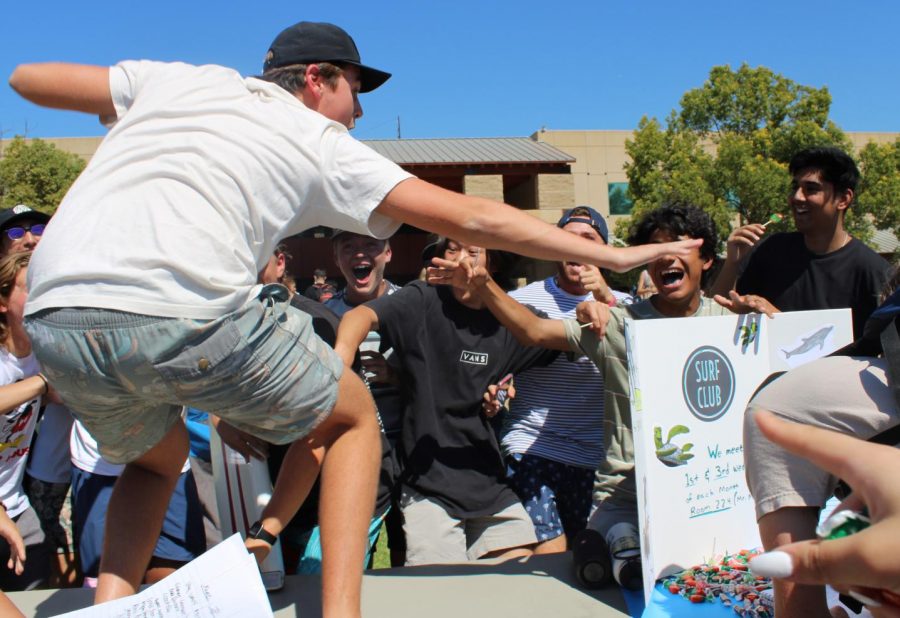 Brad Boschman, senior, rides a wave as students gather around the Surf Club table during Club Rush on Sept. 22. The multi-day event, hosted by ASB, featured presentations by 74 campus clubs.