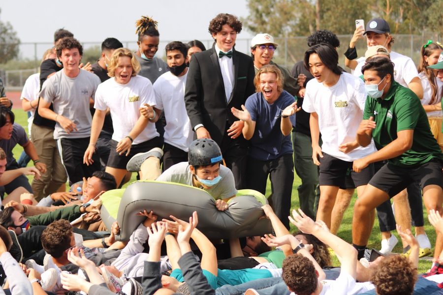 Science teacher Kurtis Chan rides a wave of seniors as Garrett Brookman, senior, and members of the senior class, cheer him on during a class versus class race at the Sept. 17 Homecoming rally.