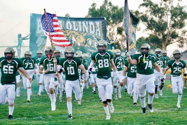 Juniors Cullen Doyle (10) and Addison Altermatt (88), and Tim Carmona (74), senior, lead Wildcats varsity football onto the field before their Sept. 8 home game against Sunny Hills High School.