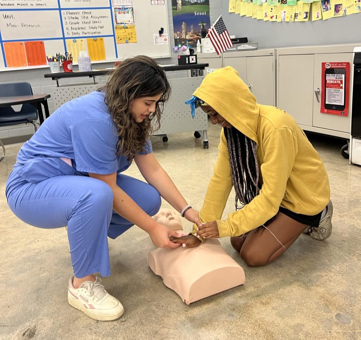 Grace Severson, senior, helps a BJH student with her hand placement on a dummy for chest compressions. HOSA board members taught the junior highs Exploring Medical Careers class how to perform CPR and use an AED on Nov. 13.