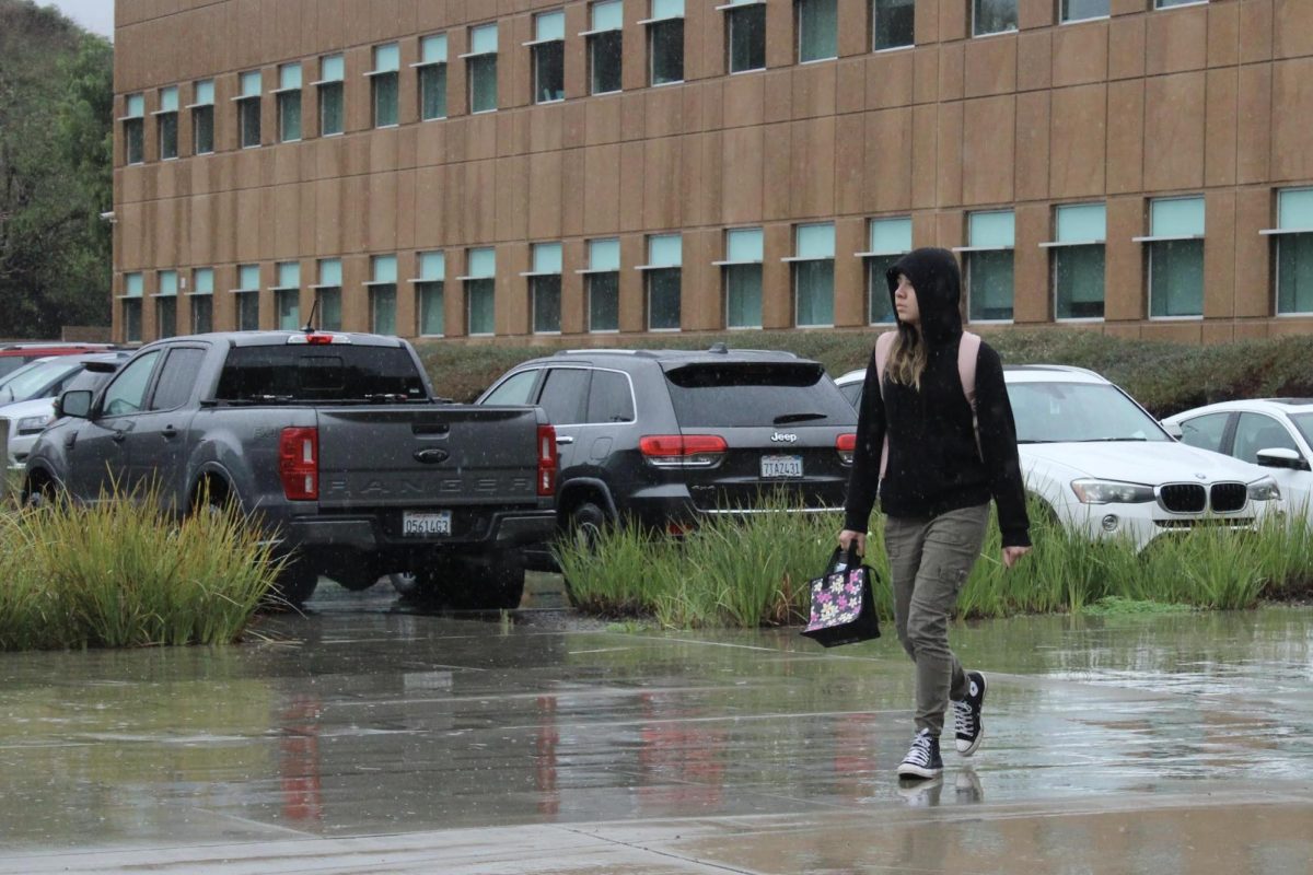 Mia Urzua, senior, walks past the New Building in the rain on Feb. 5. California experienced record-setting amounts of rainfall from Saturday to Tuesday, with Brea accumulating 6.26 inches, the most in north OC.
