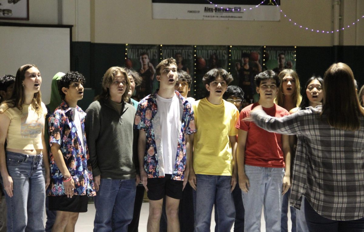 Choir director Molly Gooch leads Masquerade in a performance of the "National Anthem" to open the winter rally.