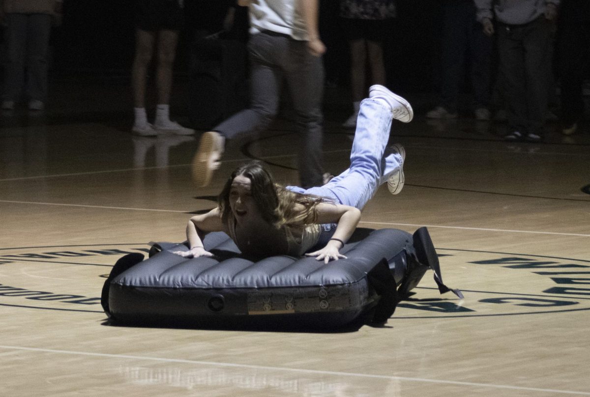 A student propels herself across the gym floor on an inflatable mattress as part of a Clash of Classes competition.