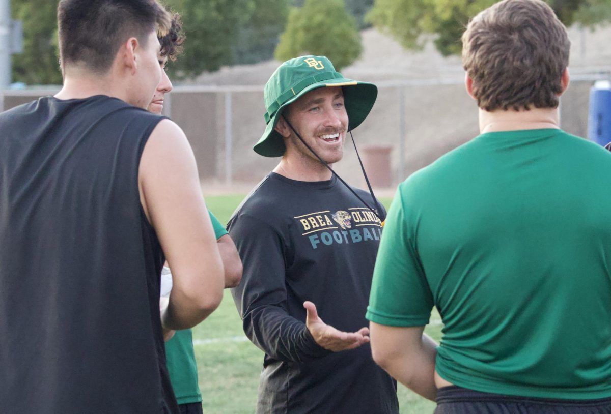 Varsity Assistant Coach Kyle Mahlstede chats with a few football players during a July 24 practice.