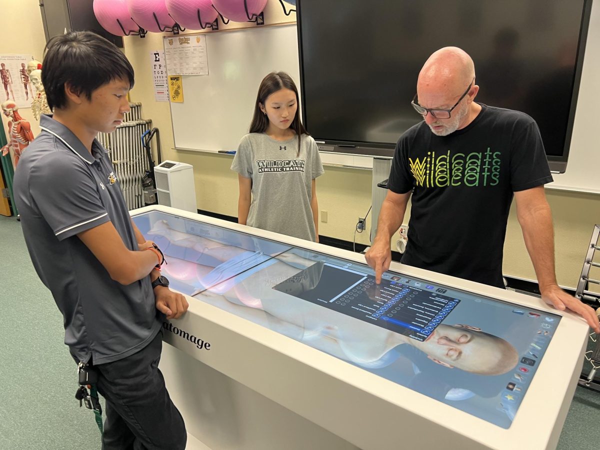 Ken McCall, Medical Careers and Sports Medicine and Therapy teacher, introduces Wildcat Medical Interns Jonathan Kwon ('27) and Emma Kim ('28) to the Anatomage table's digital  cadaver.