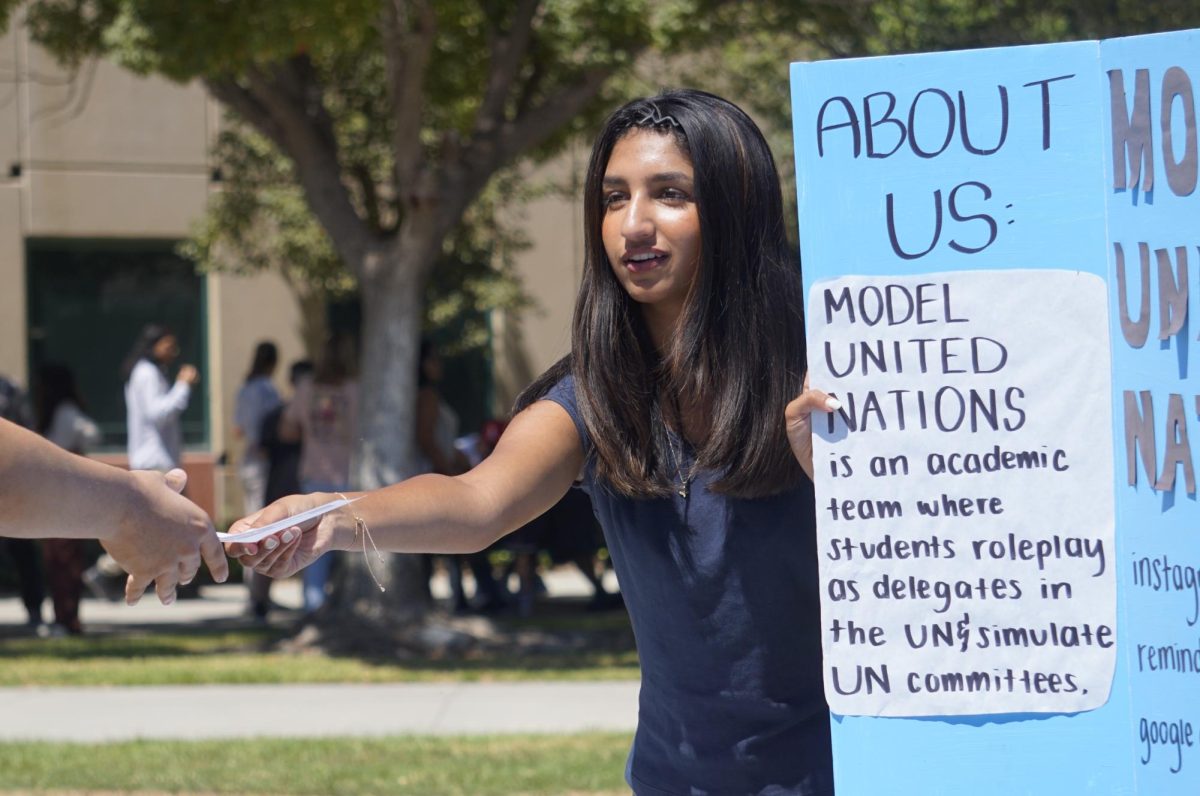 Layla Patel ('27) hands out informational material to a prospective club member at the Model United Nations table Sept. 8.