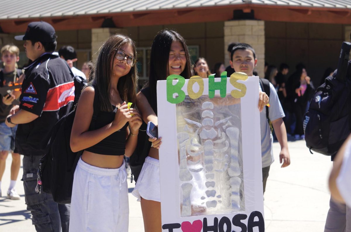 Hannah Levenson ('29) and Subi Li ('29) enjoy the "X-ray" cutout promoting Health Occupations Students of America (HOSA) in the BOHS quad Sept. 8.