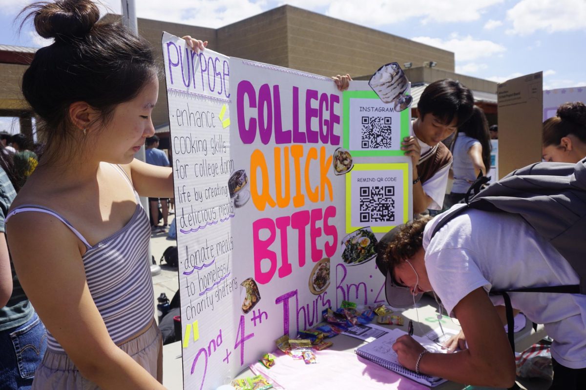 Sarah Lee ('28) watches as a student signs up for College Quick Bites Club, which teaches cooking skills for future college students, and donates prepared meals to the area's homeless.