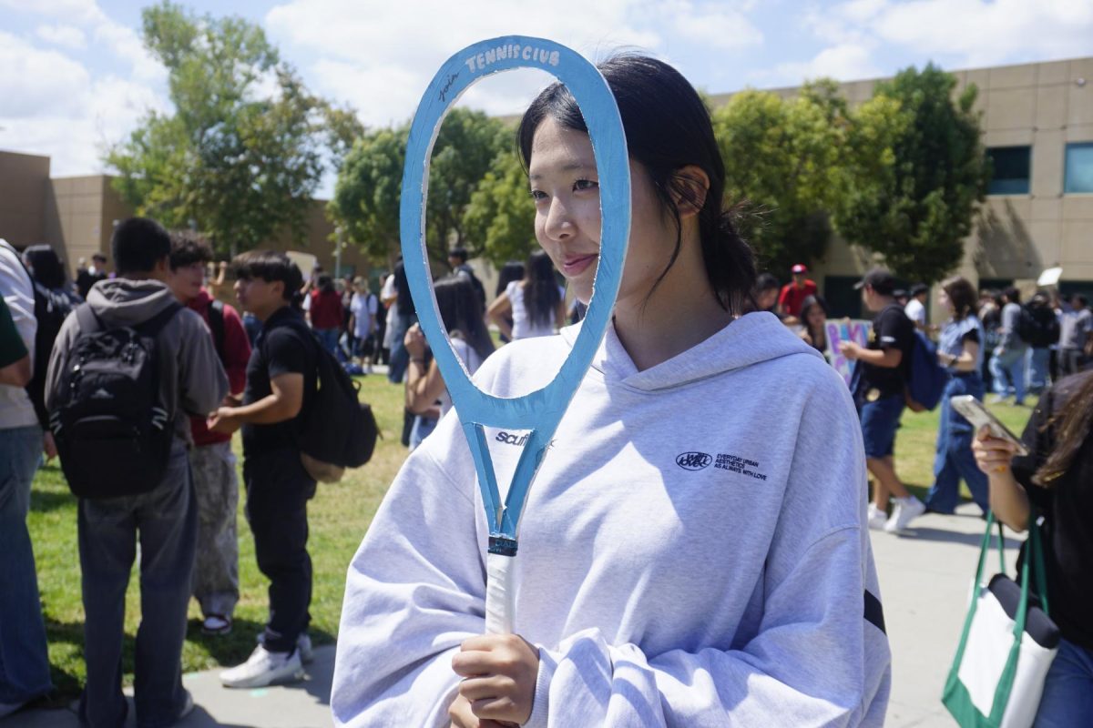Anna Kong ('28) peeks through a tennis racket, part of Tennis Club's Club Rush promotion Sept. 12.