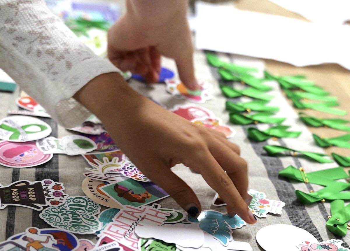 Attendees of National Alliance on Mental Illness's (NAMI) first meeting collect stickers and green ribbons in the PAWS WellSpace Sept. 25. 