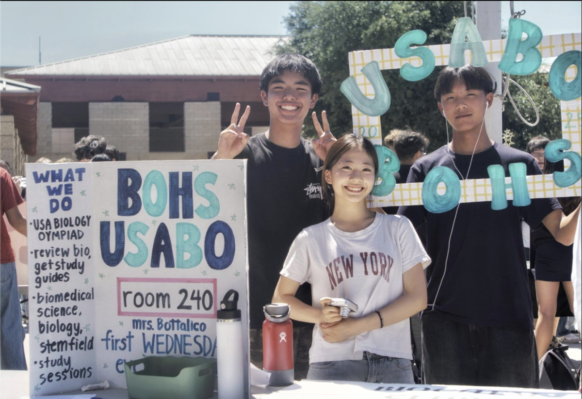 Ryland Chang (‘28), Raina Kim (‘28) y Brandon Wang (‘28) detrás de su mesa para el Club USA Olímpico de Biología (USABO) el 8 de septiembre. 