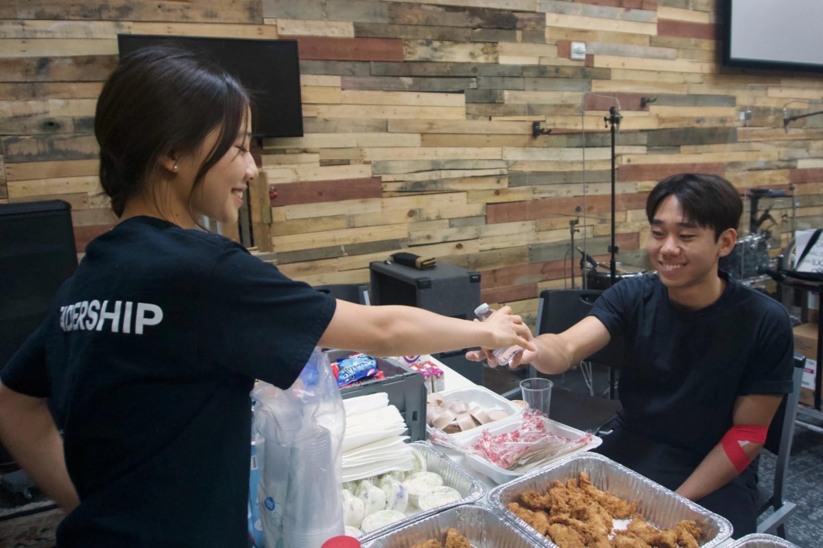 BOHS Red Cross public relations officer Raina Kim (’28) hands water to club president Sean Yoon (’26) following his blood donation during the club’s Oct. 2 blood drive at North Hills Church in Brea.