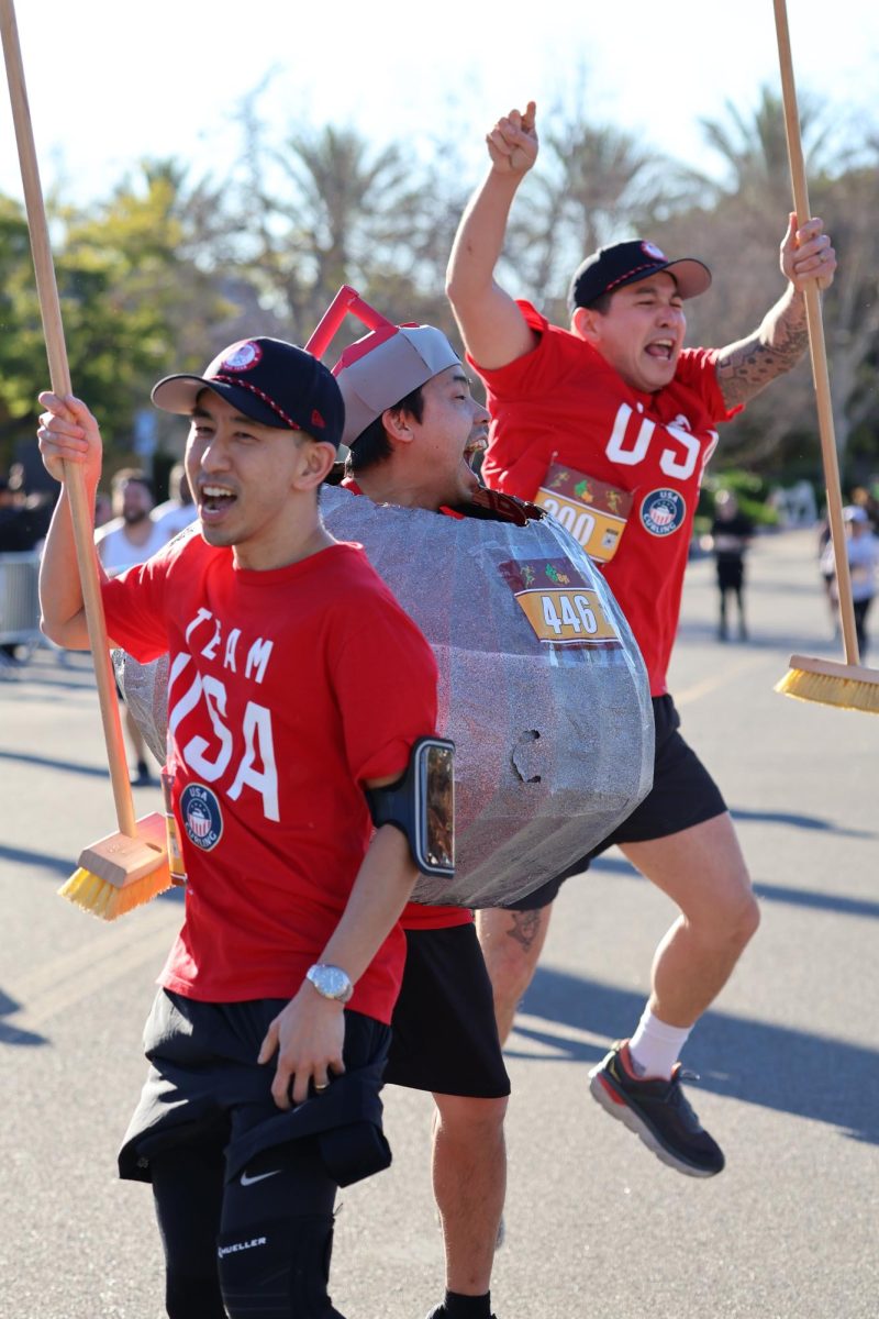 Brea 8K participants dressed as Team USA Olympic curlers and a curling stone celebrate after completing the race.
