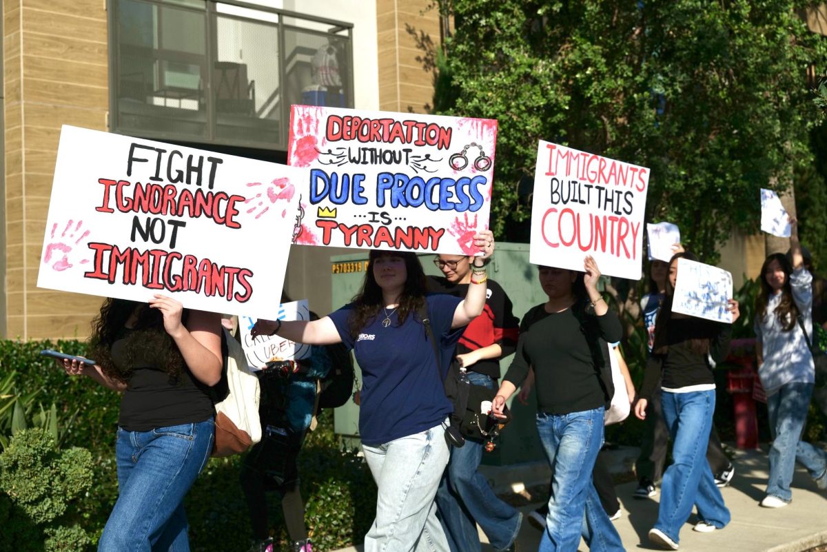 Holding up hand-made signs, BOHS students walk past the Avalon Brea Place apartments during a student-led walkout Feb. 6. 
