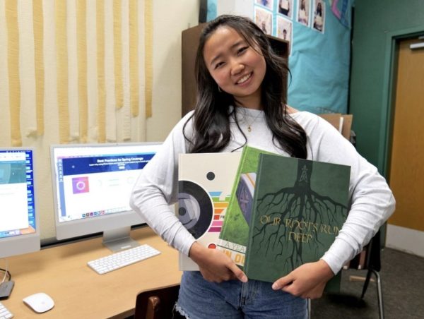 'Gusher' Editor-in-Chief Claire Yoo ('26) cradles her past yearbook editions in the yearbook room. 